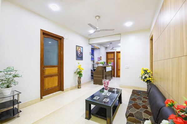 A reception area with a reception desk, a seating area with a sofa, a coffee table, and a potted plant. - FabHotel The Lalit Vibes - Nr. DLF Phase 2 & MG Road Metro (Gurugram)