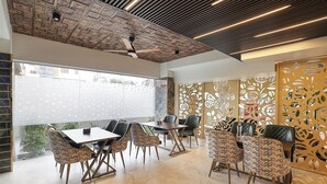 Un espace de salle à manger moderne, doté d’un ventilateur de plafond, de motifs décoratifs sur les murs et offrant une vue par une fenêtre.