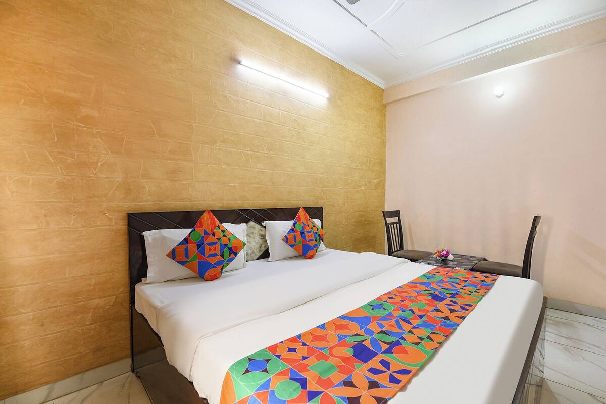 Hotellihuone, jossa on suuri sänky, puinen pääty ja koristeellinen koristetyyny.