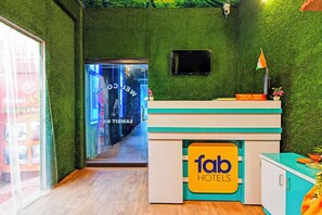A reception desk with a sign for 'fab hotels', a small flag, and a security camera on the wall.