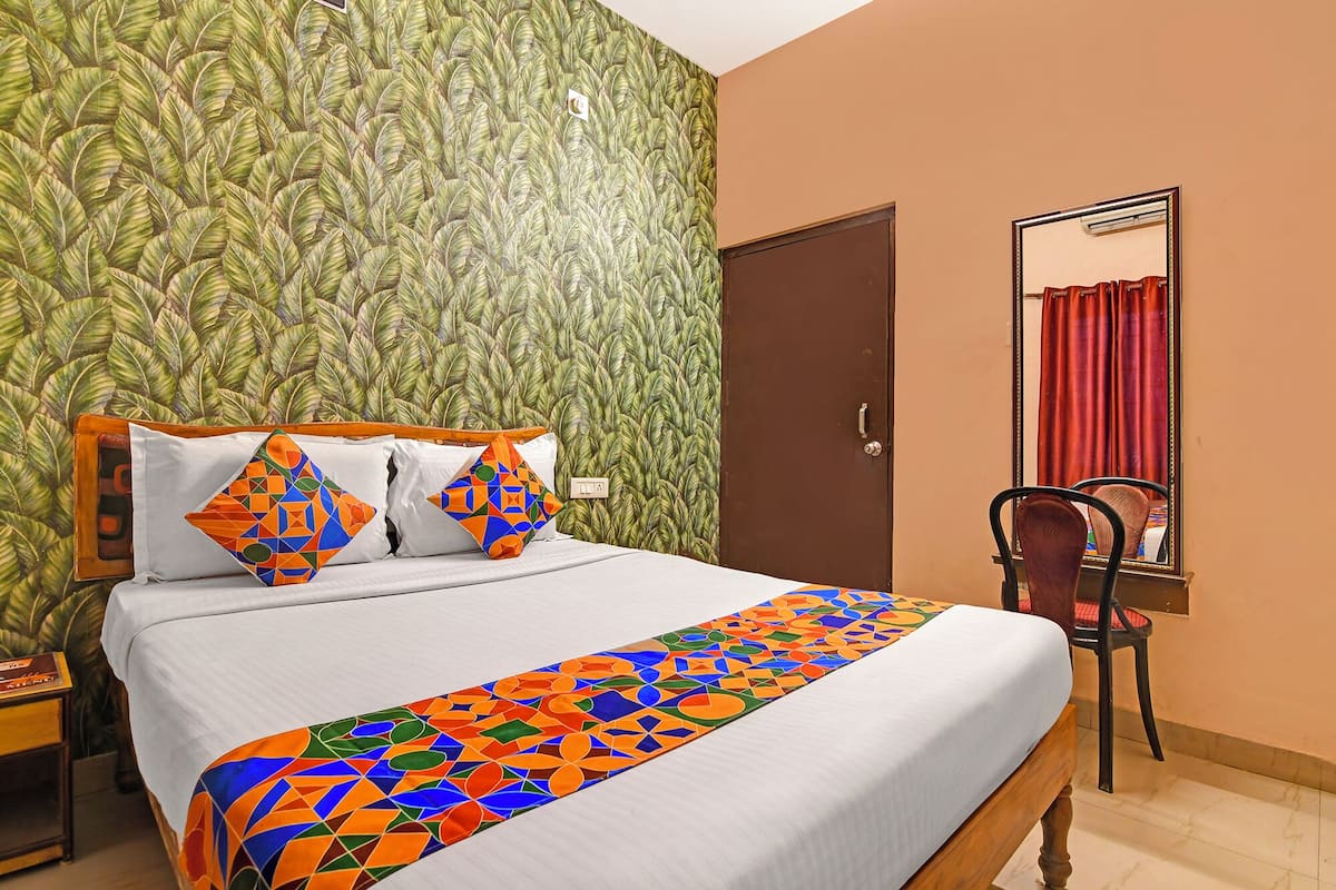 Een hotelkamer met een bed, een spiegel en een stoel.