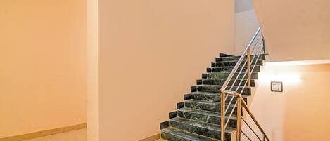A staircase with marble steps and metal railings, leading to an upper floor.