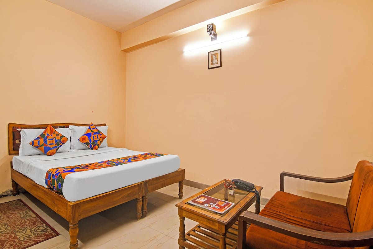 Een slaapkamer met een houten bed, een klein tafeltje met een boek en een stoel.