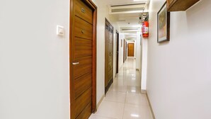 A hallway with wooden doors, a fire extinguisher, and a ceiling vent. - Fabhotel Rahat (Mumbai)