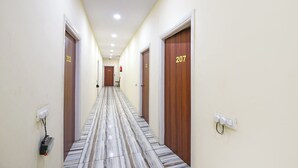 A hotel hallway with numbered doors, a marble floor, and a ceiling with recessed lighting. - Fabhotel High View (Faridabad)