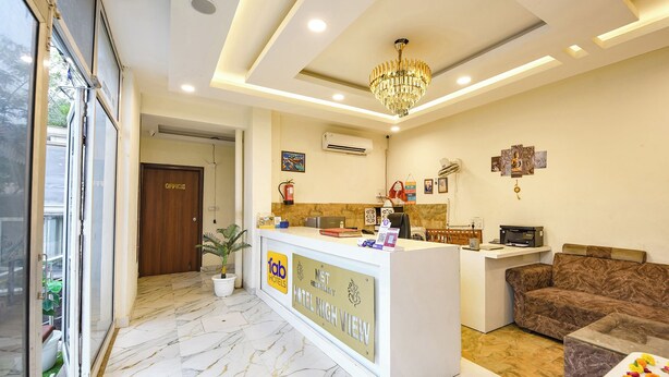 A hotel reception area with a marble floor, a reception desk, a chandelier, and a brown sofa. - Fabhotel High View (Faridabad)
