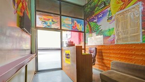 Een hotel receptie met een houten balie, een bank en kleurrijke kunst aan de muren.