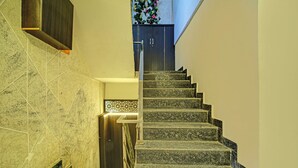 Una escalera con barandilla que lleva a una puerta oscura con un panel decorativo encima.