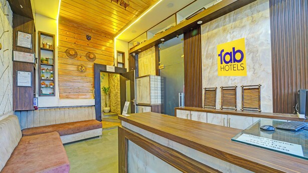 Área de recepção de hotel com balcão de madeira, espaço de espera com bancos e um letreiro fixado na parede para 'fab hotels'.