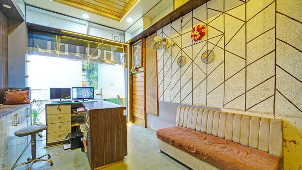 A modern office space with a wooden desk, computer, and a cushioned bench. - FabHotel Alexa (Bhopal)