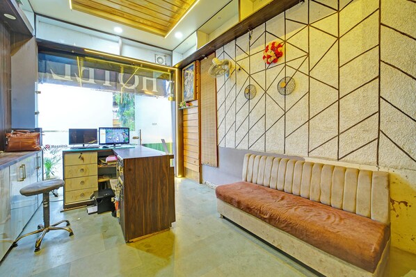 A modern office space with a wooden desk, computer, and a cushioned bench. - FabHotel Alexa (Bhopal)