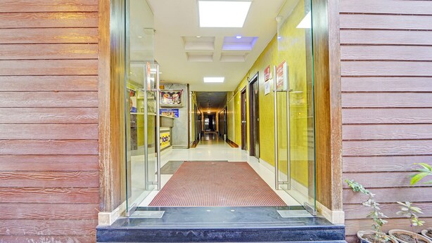 A hotel entrance with a glass door, a red carpet, and a hallway leading to rooms. - Fabhotel Maruthi (Coimbatore)