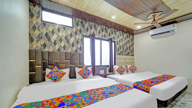 A hotel room with two beds, a wooden ceiling, and a patterned wall. - Fabhotel Starlight Inn (Ujjain)