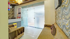 A hotel lobby with a reception desk, a chandelier, a patterned wall, and a sofa with a decorative pillow. - Fabhotel Starlight Inn (Ujjain)