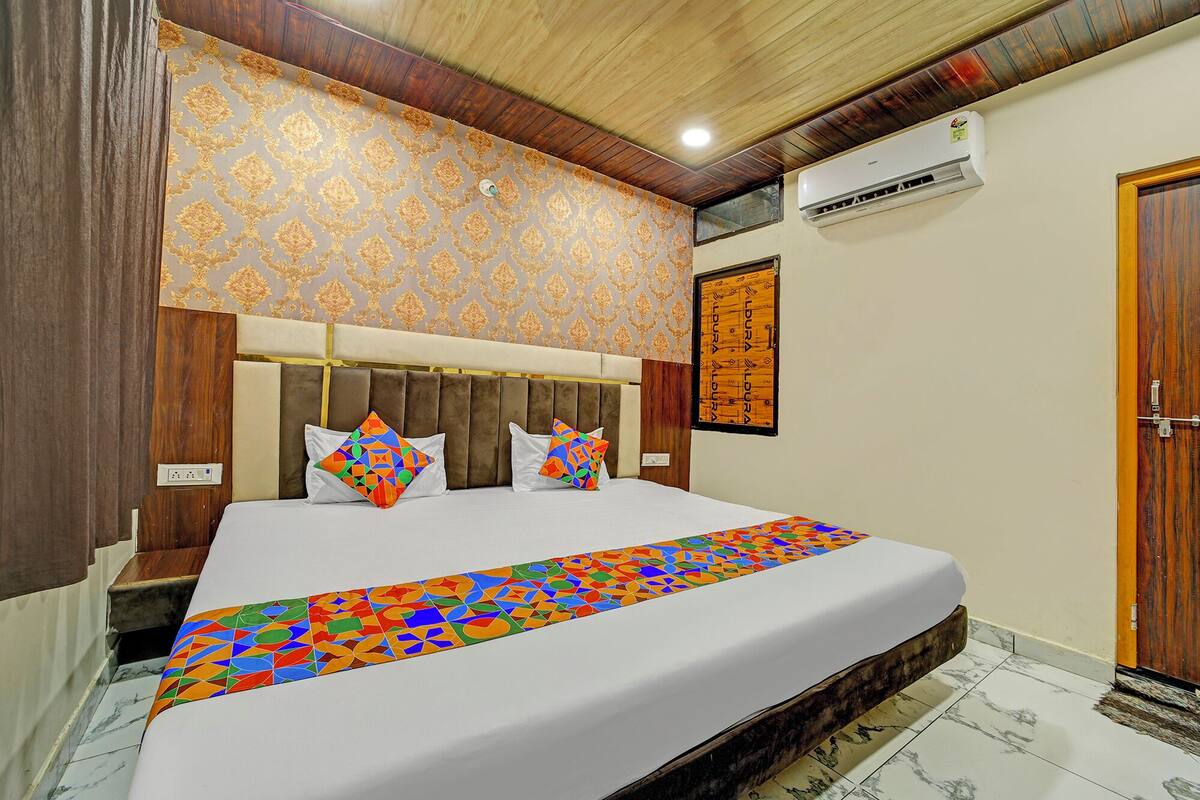 A bedroom with a large bed, a wooden headboard, patterned wallpaper, and a wooden door.