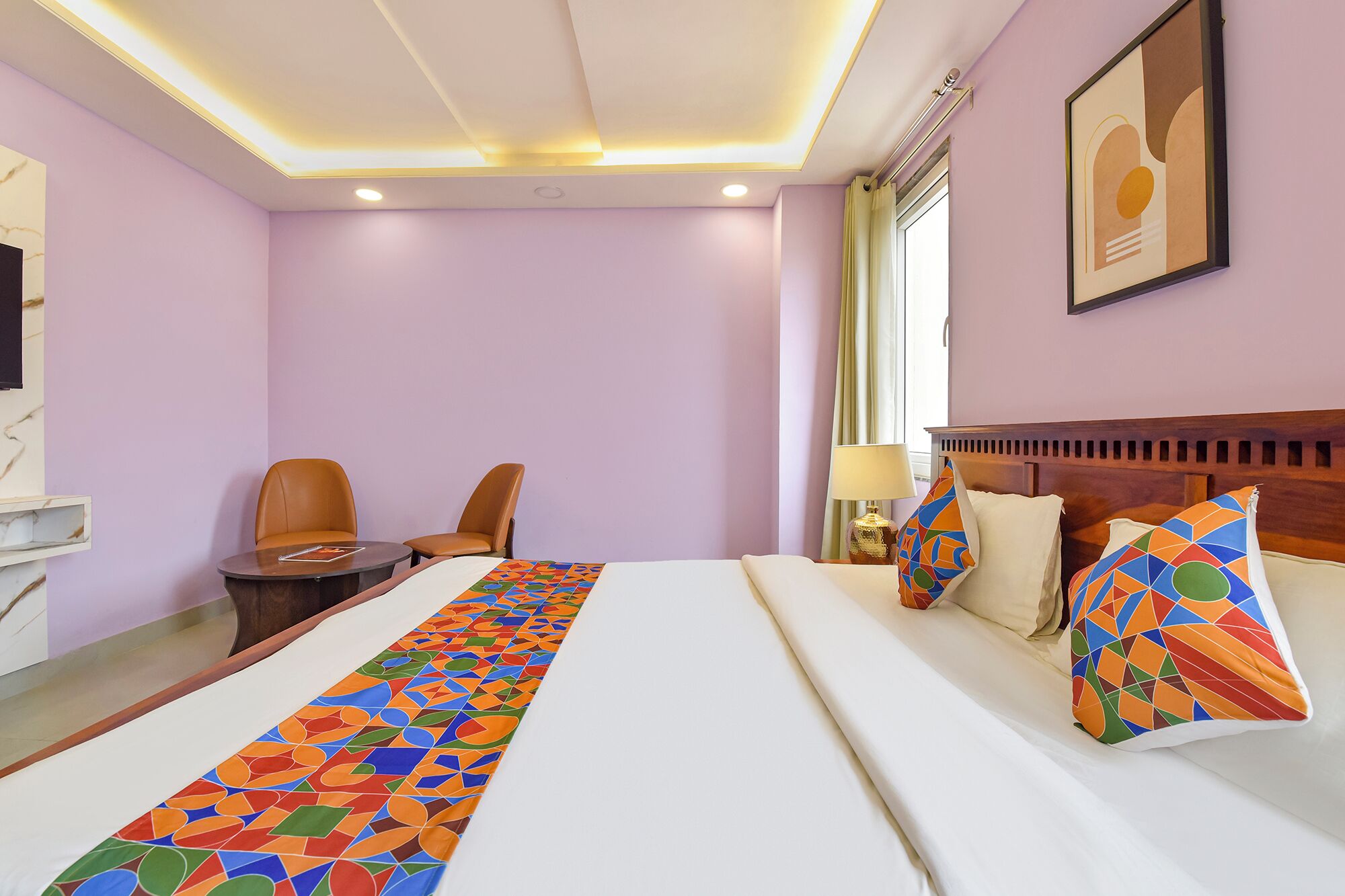 Una habitación de hotel con una cama, dos sillones, un escritorio, una lámpara y un cuadro en la pared.