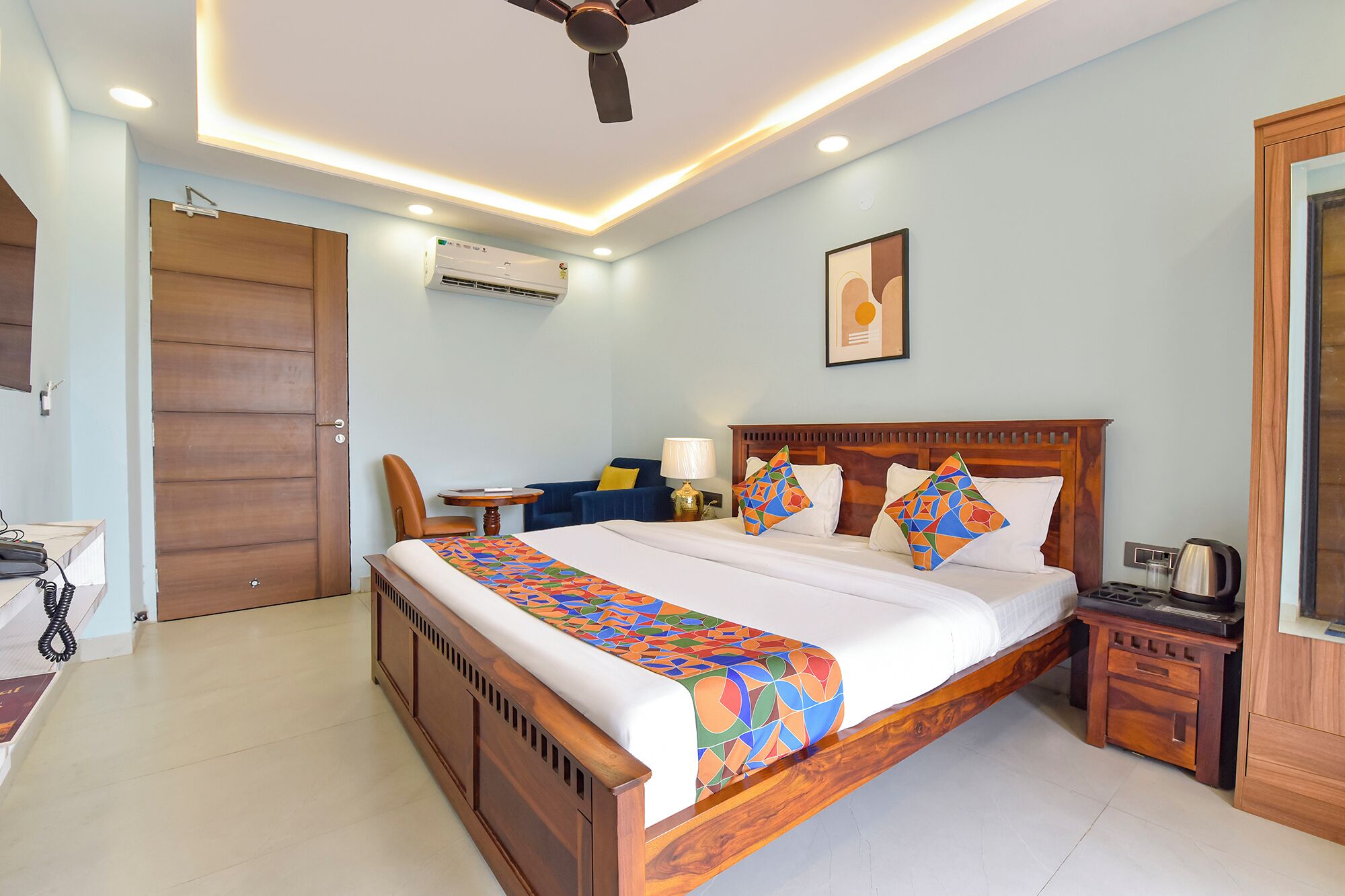 A hotel room with a wooden bed, a desk, a chair, a nightstand, and a ceiling fan.