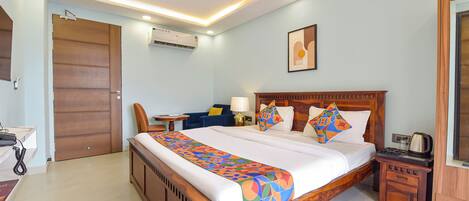 A hotel room with a wooden bed, a desk, a chair, a nightstand, and a ceiling fan.