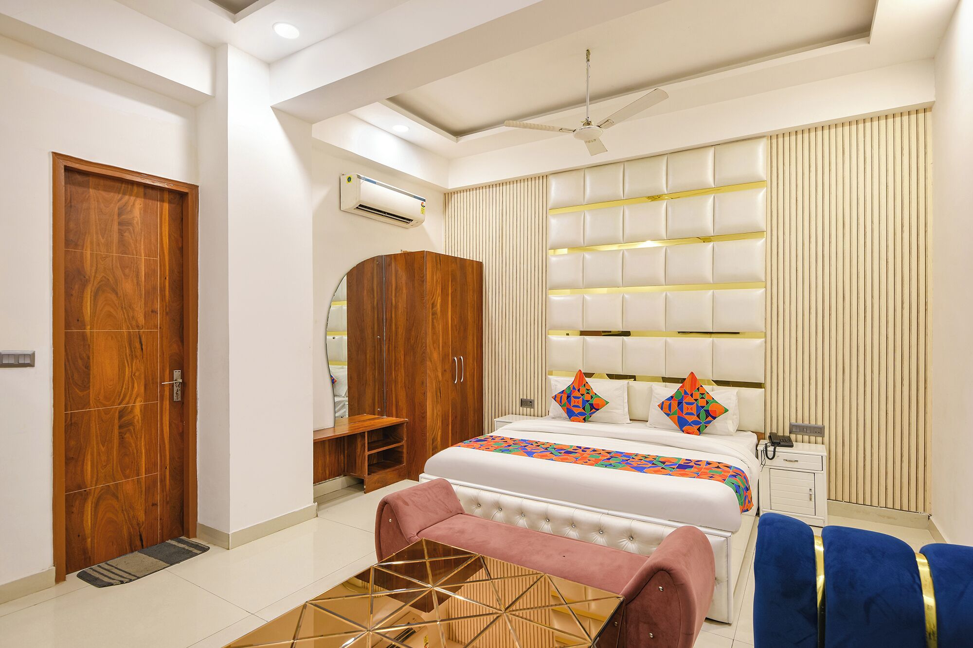A modern bedroom with a bed, a wardrobe, a vanity, and a ceiling fan.