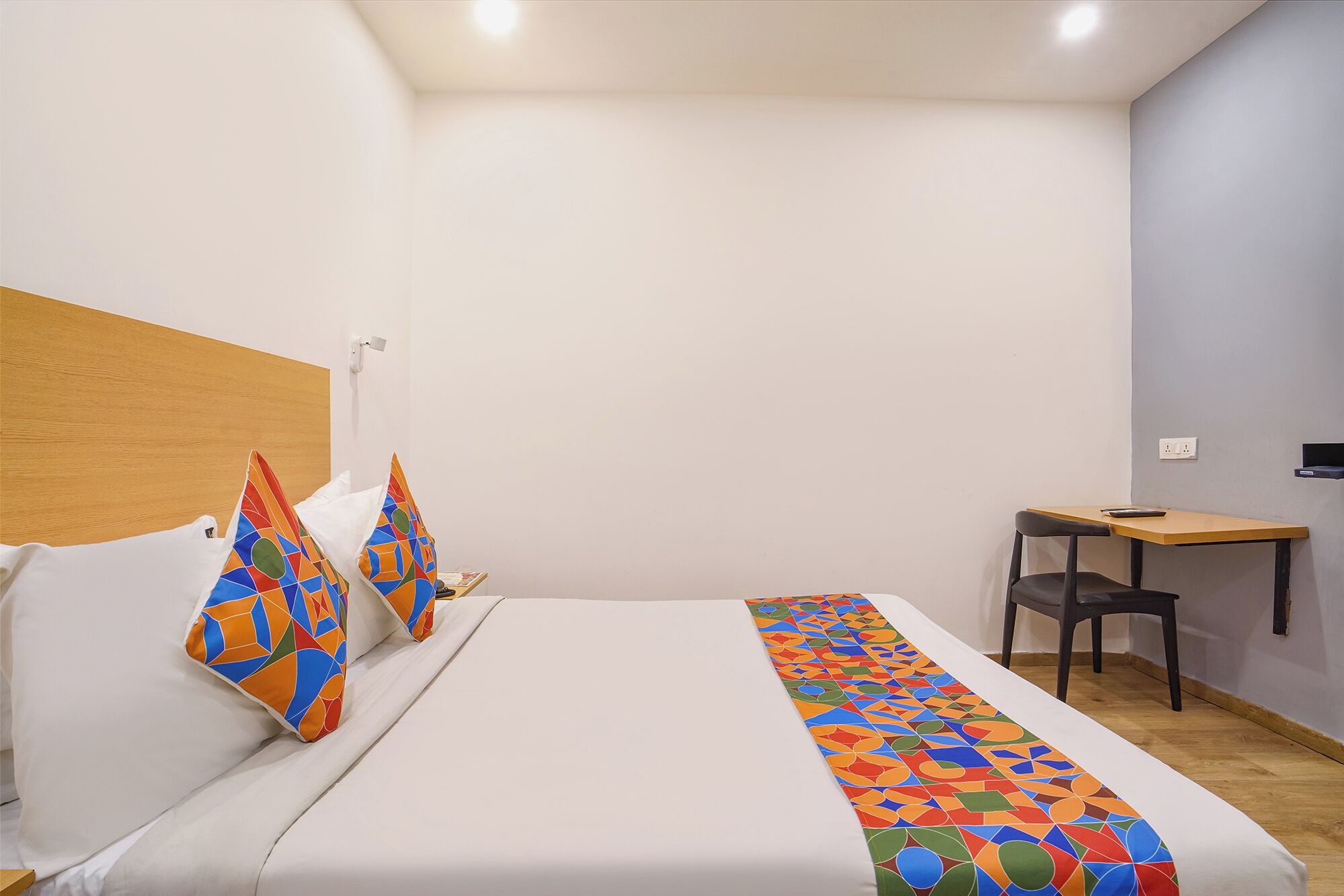A hotel room with a bed, a desk, and a chair.