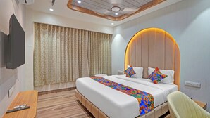 Una habitación de hotel moderna con una cama grande, un televisor montado en la pared, un escritorio con un control remoto y una silla.