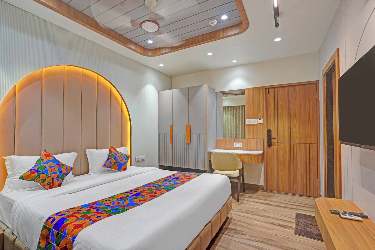 A modern hotel room with a large bed, a desk, and a wardrobe.