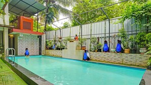 A swimming pool with a metal roof, surrounded by potted plants and a statue. - Fabhotel Tranquil Inn (Calangute)