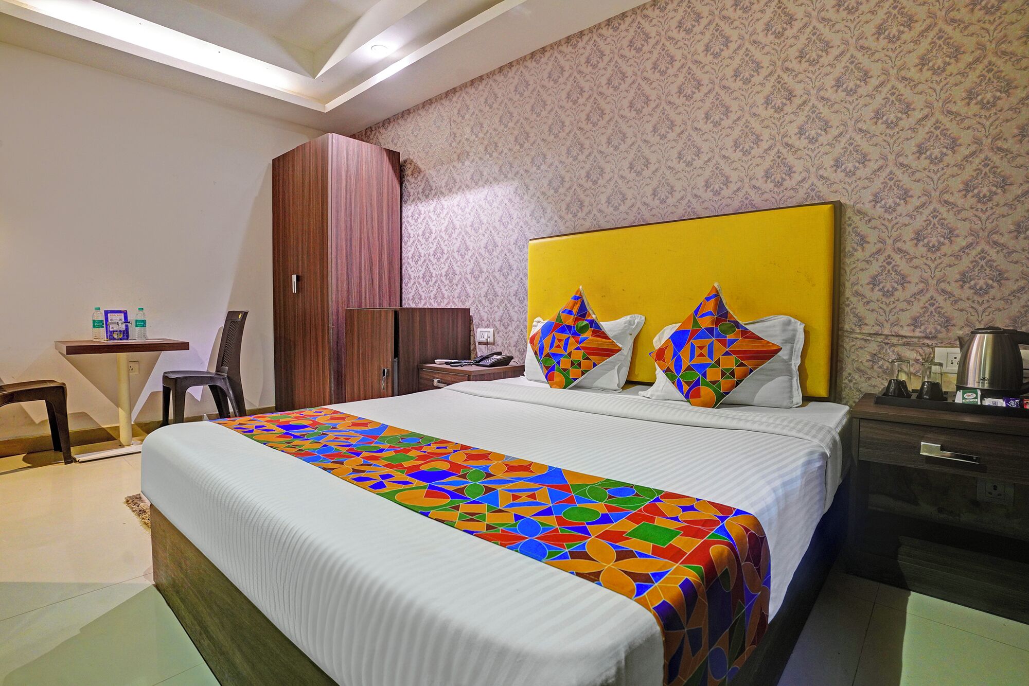 Une chambre d’hôtel avec un grand lit, un bureau, une armoire et un papier peint à motifs.