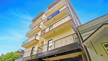 Un edificio de varios pisos con balcones, un bar y restaurante en la planta baja, y un letrero que dice 'Tranquil Inn'.