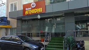 Ett hotell som heter ”Hotel ATHIDHI”, med en modern fasad, en trappa som leder upp till entrén och en parkerad bil framför.