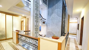 Una maestosa scalinata con ringhiere elaborate, un pavimento in marmo con motivi geometrici e un soffitto alto con illuminazione incassata.