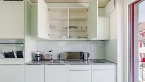 A modern kitchen with white cabinets, a built-in microwave, a coffee maker, and a toaster.