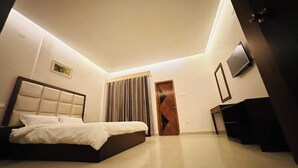 A modern bedroom with a large bed, a television, and a door. - Shayan Resort (Singair)