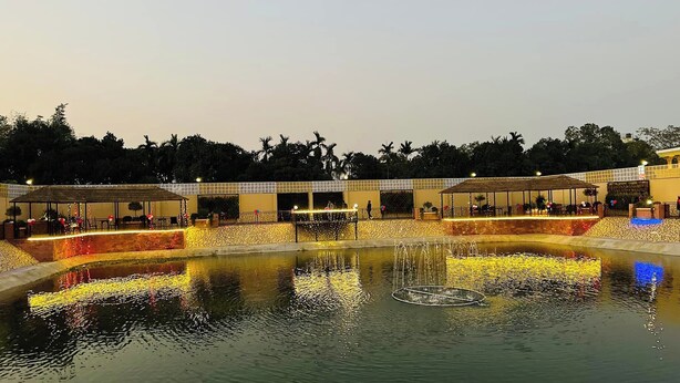 A well-lit outdoor area with a water feature, seating areas, and a covered walkway. - Shayan Resort (Singair)