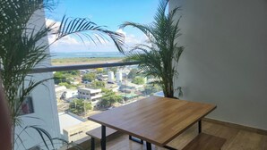 A balcony with a wooden table and bench, overlooking a cityscape with buildings and greenery. - Exclusive apartment Cartagena de Indias. (Cartagena de Indias)