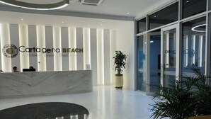 A modern lobby with a reception desk, a large potted plant, and a glass door entrance. - Exclusive apartment Cartagena de Indias. (Cartagena de Indias)