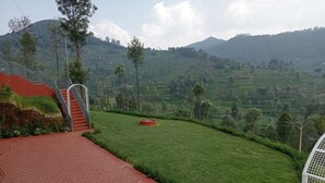 A terraced hillside with a paved pathway leading to a staircase. - Heavenly Hills (Kotagiri)