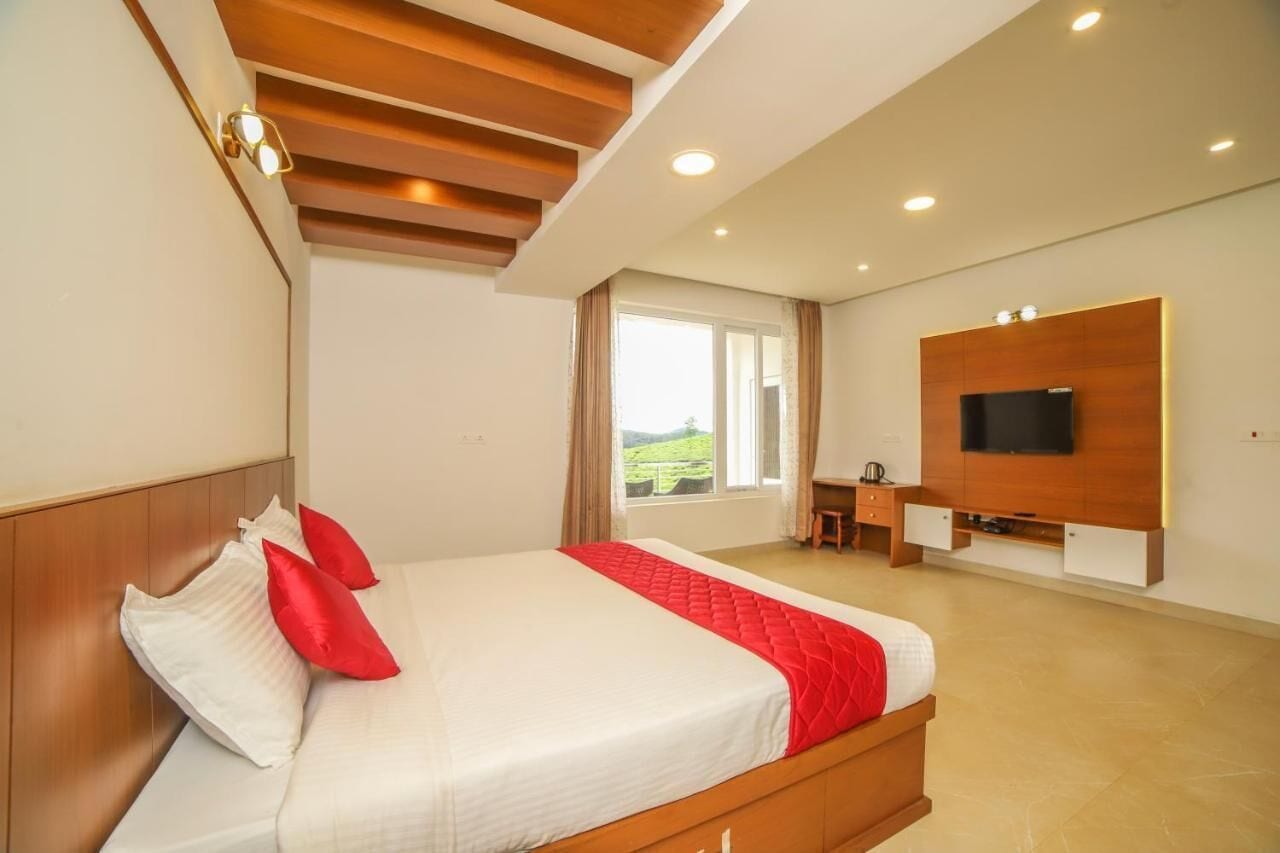 A modern hotel room with a large bed, a flat-screen TV mounted on the wall, and a desk with a chair.