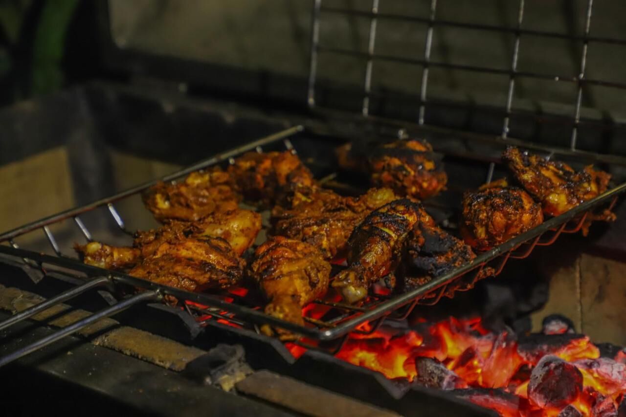 Una parrilla con pollo cocinándose a fuego abierto.