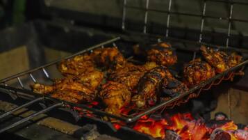 Ein Grill mit Hähnchen, das über offenem Feuer zubereitet wird.