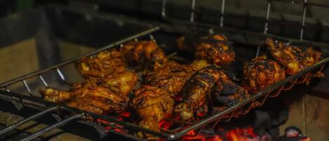 Una parrilla con pollo cocinándose a fuego abierto.
