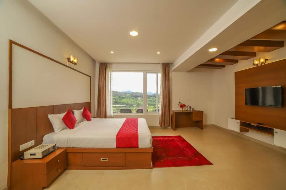 A modern hotel room with a large bed, a television, and a view of the outdoors.