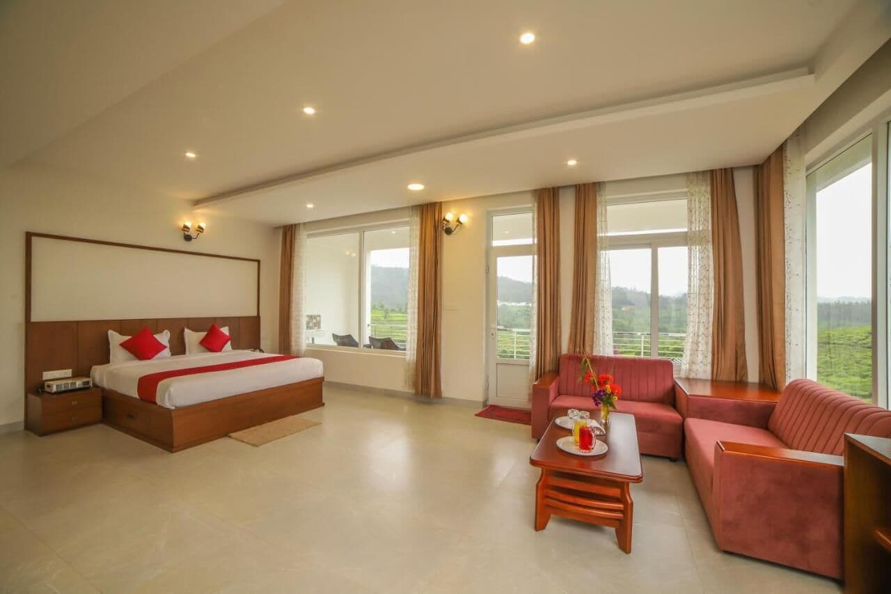 Amplia habitación de hotel con una cama grande, un sofá, una mesa de centro y vistas al exterior.