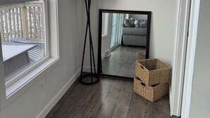 A room with a large window, a floor lamp, a mirror, and wicker baskets. -  Lakefront Cottage on Lake Winnebago (Hilbert)