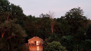 A two-story house with a balcony, surrounded by dense trees and a body of water. -  Lakefront Cottage on Lake Winnebago (Hilbert)