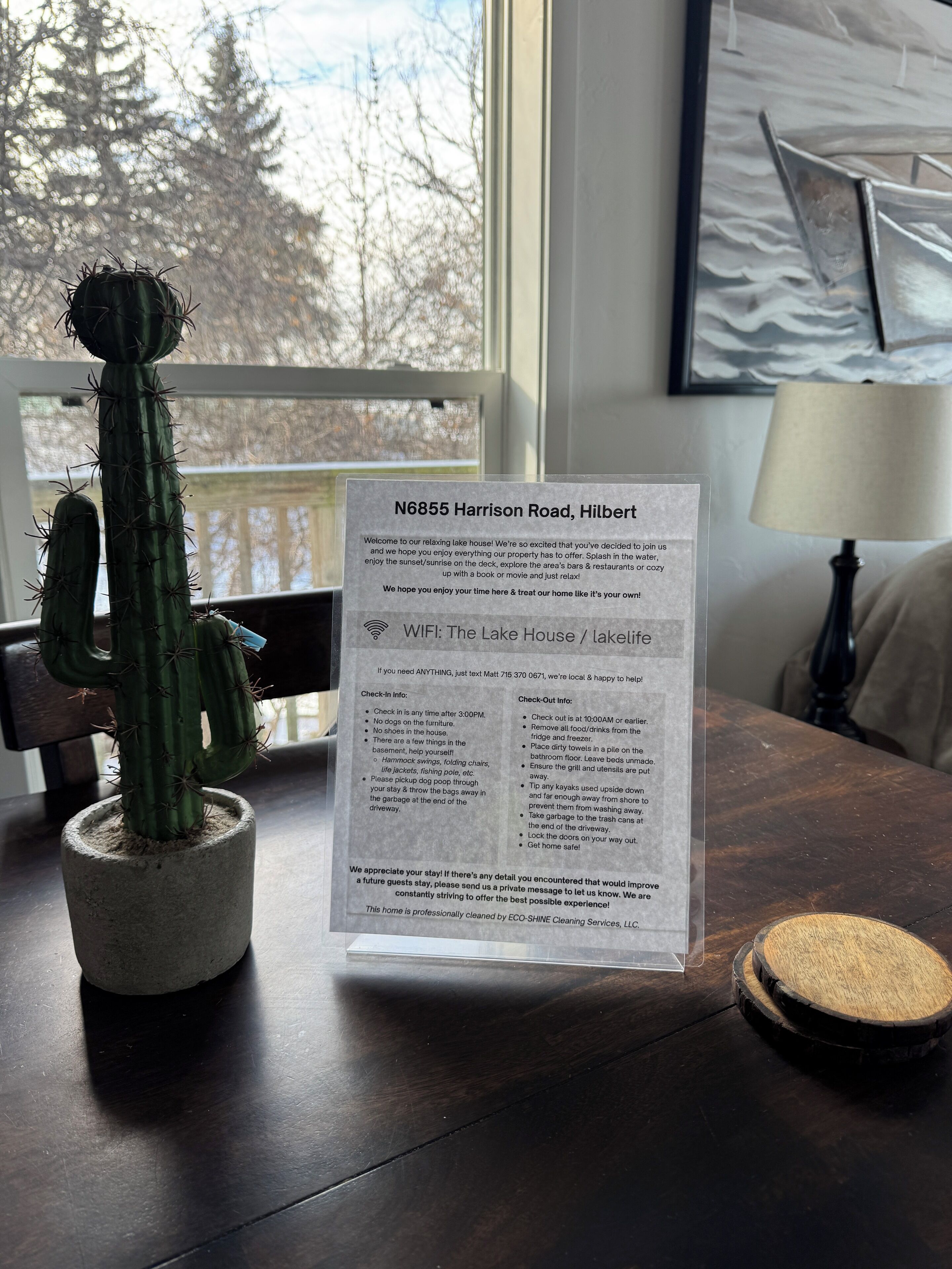 A cactus in a pot on a wooden table with a printed check-in information card.