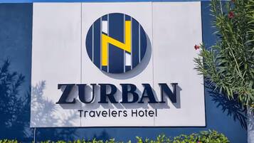 Schild für das ZURBAN Travelers Hotel mit einem markanten 'H'-Logo.