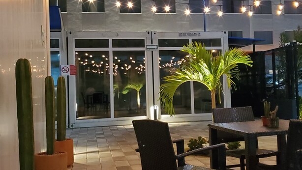 An outdoor patio area with a seating arrangement, potted plants, and string lights. - ZURBAN TRAVELERS (Paraíso)