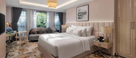 A hotel room with a large bed, bedside tables, a desk with a chair, a television, and a wardrobe.