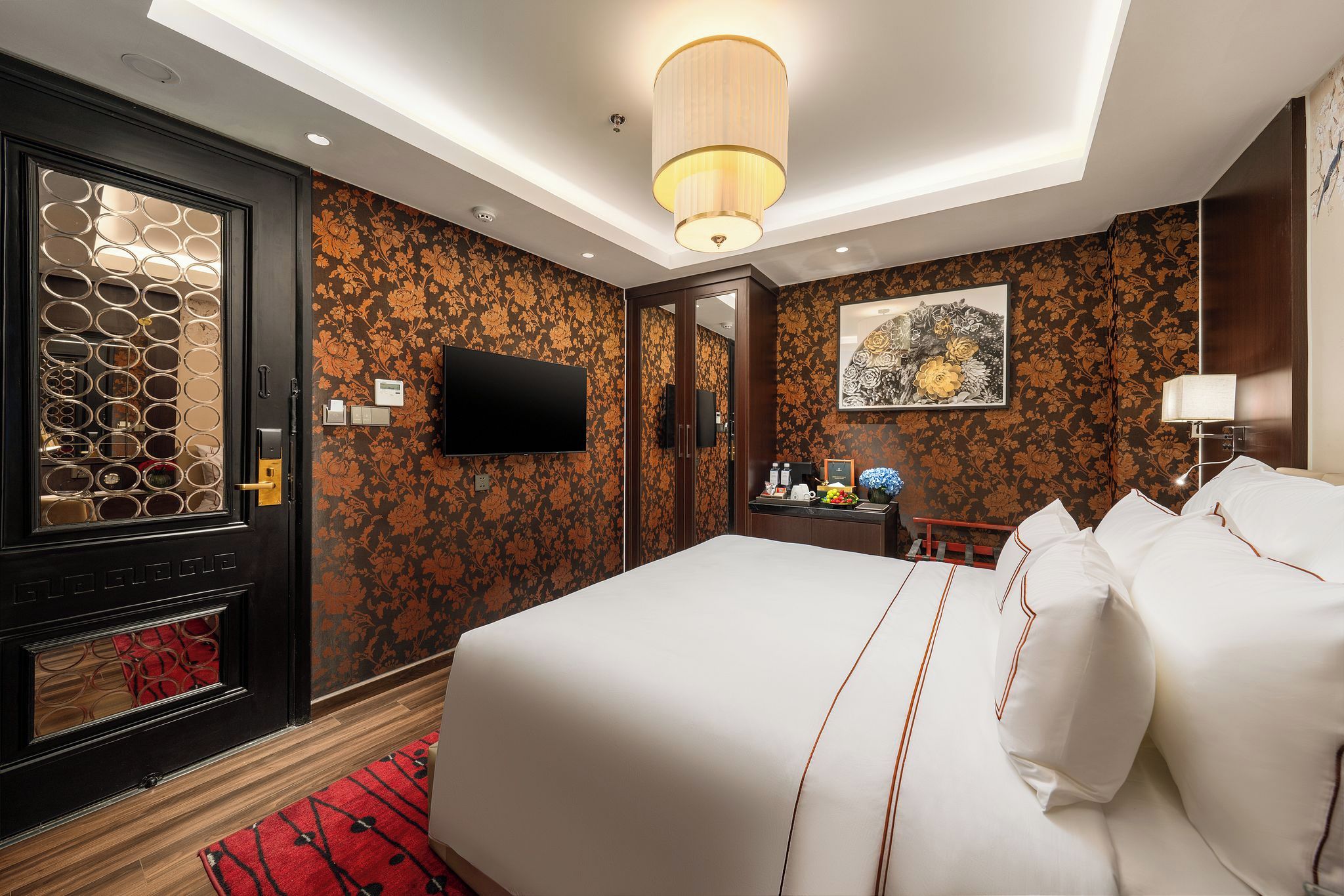 A hotel room with a large bed, a TV, a desk, and a mirror.